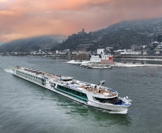 Flusskreuzfahrtschiff vor Berg mit Schnee
