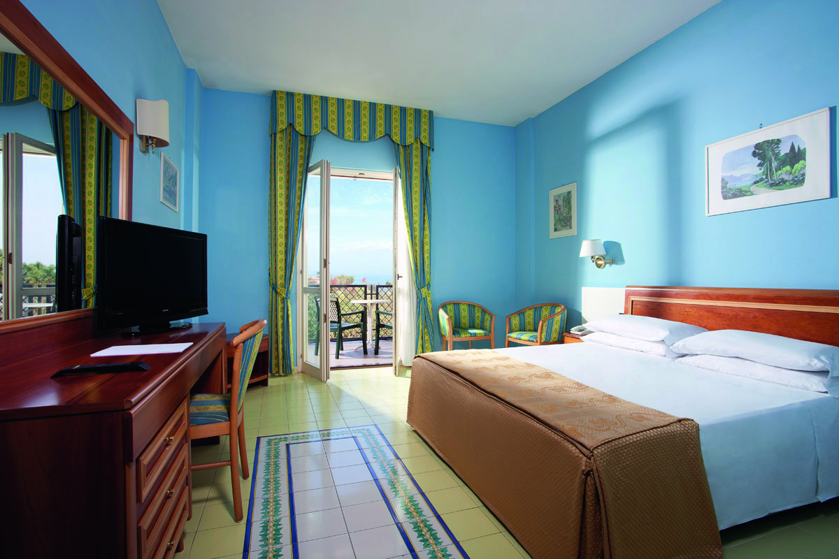 Hotelzimmer mit blauem Anstrich und einem Doppelbett