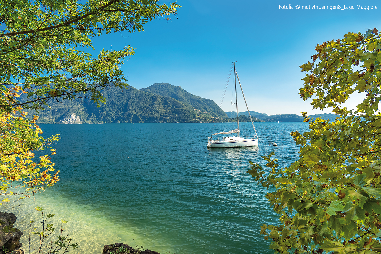 Ausblick auf einen Berg, der sich hinter einem Meer befindet auf dem ein Segelboot fährt