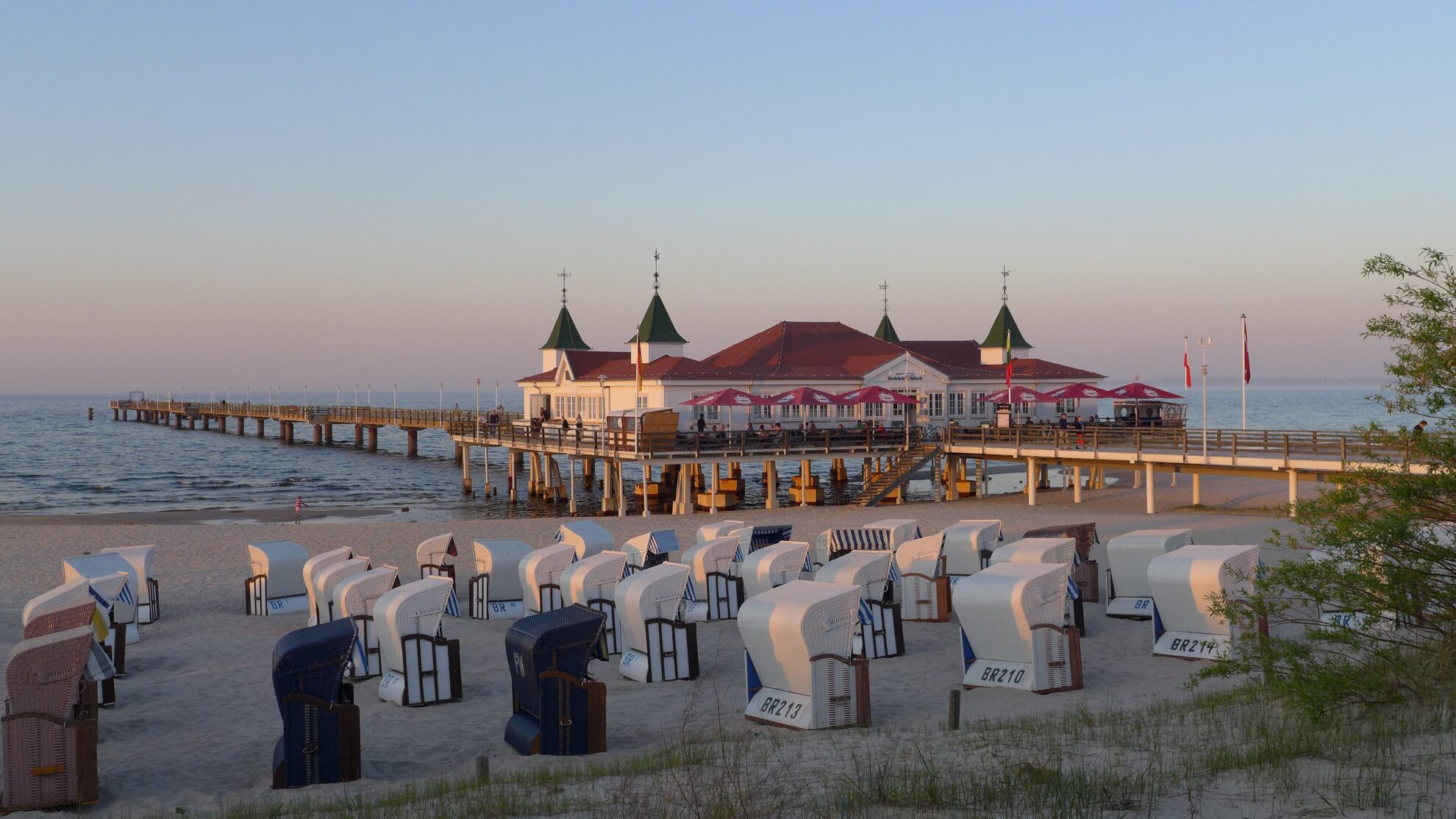 Strandkörbe am Strand und ein Haus auf einer Brücke
