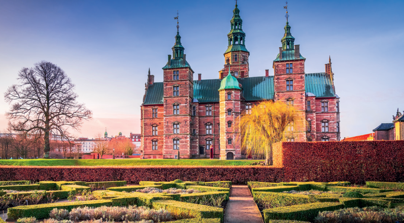 Vor einem Schloss ist eine angelegter Garten.