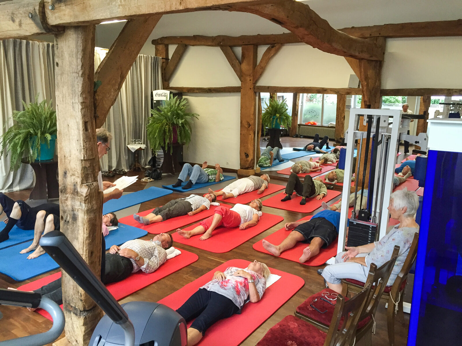 In einem Altbau liegen viele Menschen auf Gymnastik-Matten und machen einen Kurs