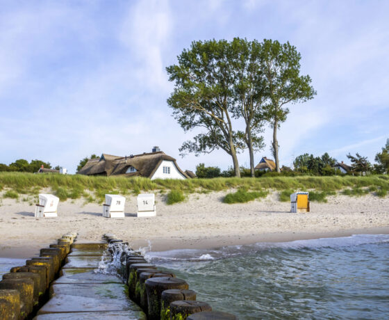 Strand mit Strandkörben und weißen Häusern im Hintergrund
