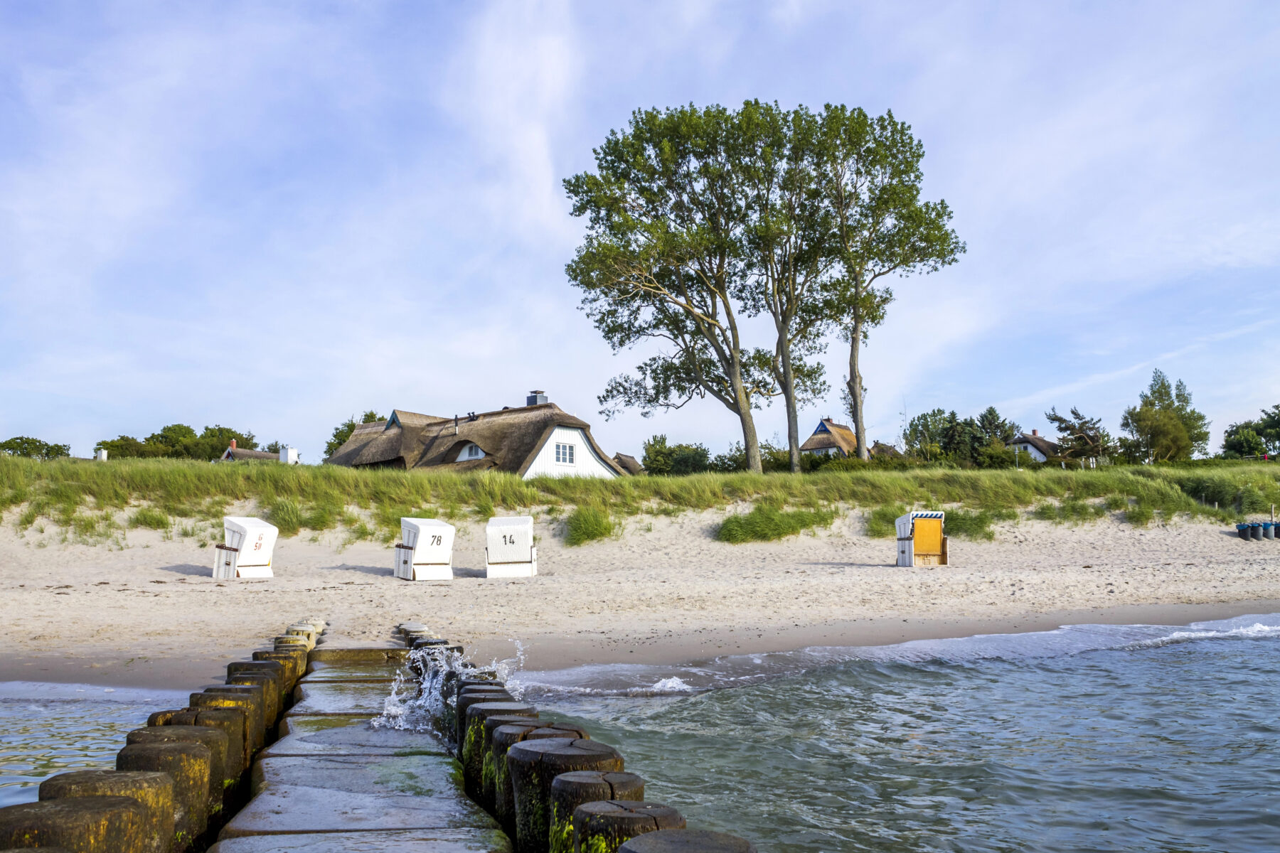 Strand mit Strandkörben und weißen Häusern im Hintergrund